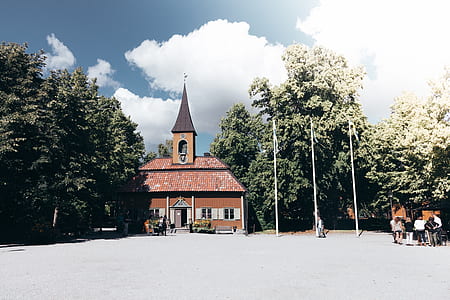 brown chapel surrounded by trees near poles thumbnail