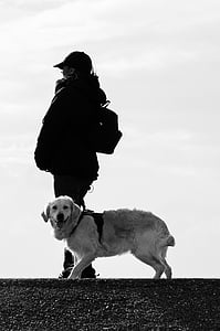 grayscale photography of person standing beside golden retriever during daytime thumbnail