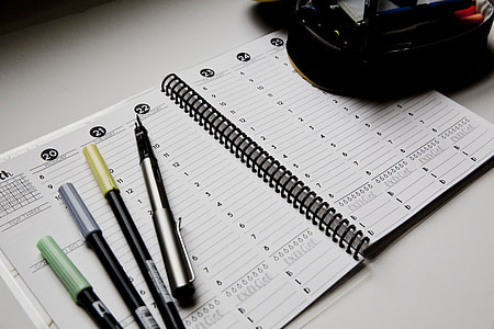 four pens placed on top of planner notebook thumbnail