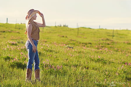woman standing on grass field holding her hat during daytime thumbnail