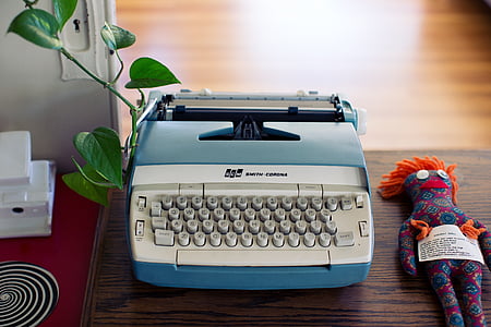 blue and gray typewriter on brown table thumbnail
