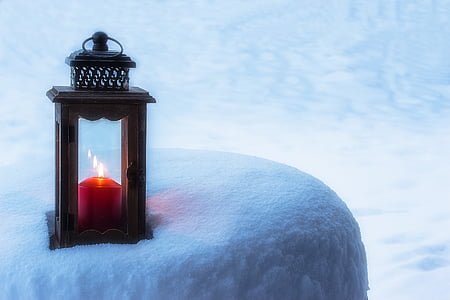 black wooden candle holding with red lit candle inside placed on frosted surface thumbnail