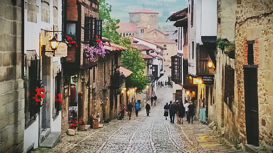 photo of people walking near brown painted village under white and blue sky thumbnail