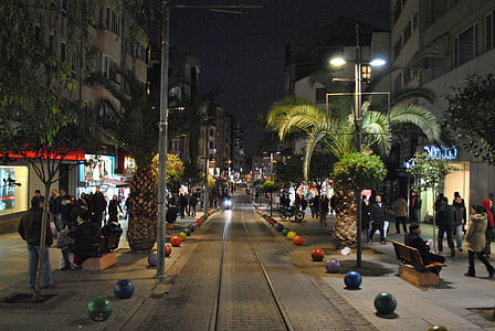 people walking near street beside concrete buildings at nighttime thumbnail