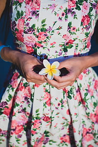 Woman in White and Green Floral Dress Holding Flower thumbnail