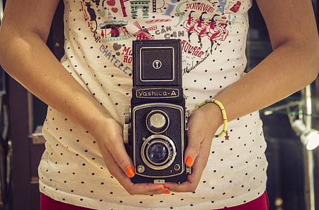 woman holding black Yashico-A reflex camera thumbnail