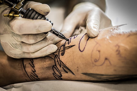 person holding black and gold tattoo machine thumbnail