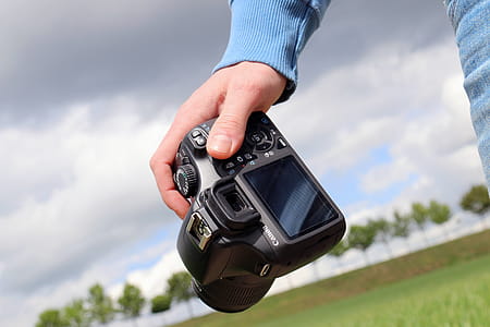 Detail of hand that holds DSLR camera in landscape thumbnail