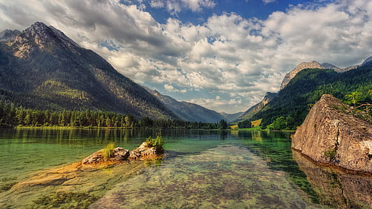 body of water near mountain covered with trees thumbnail