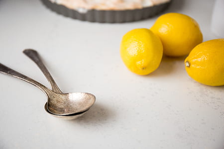 two stainless steel spoon beside lemons on top of table thumbnail
