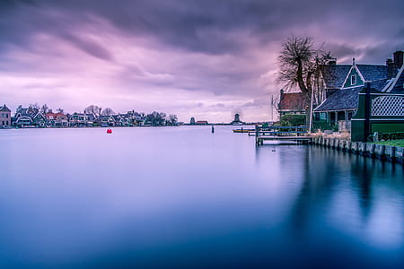 house near body of water under dark clouds thumbnail