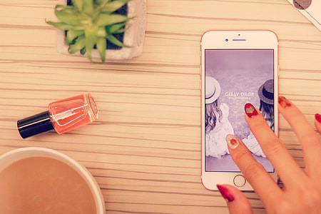 person with red manicure touching screen of rose gold iPhone 6s thumbnail