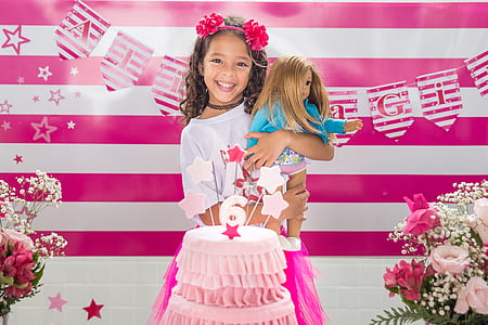 girl carrying doll in front of cake thumbnail
