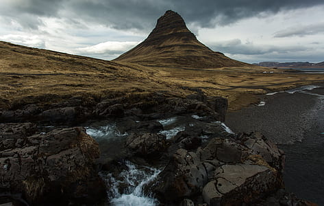 river near rock formation under cloudy sky thumbnail