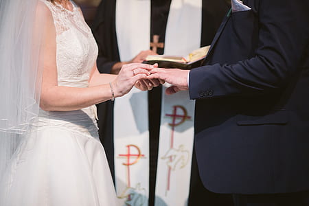 bride putting ring on groom's finger thumbnail