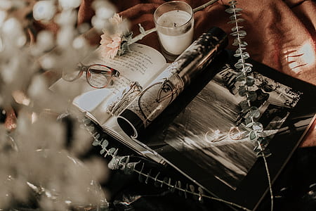 flat lay photography of opened magazine and book near candle and eyeglasses thumbnail