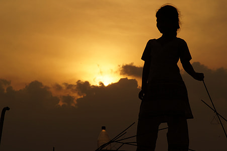 silhouette of woman standing during orange sunset thumbnail