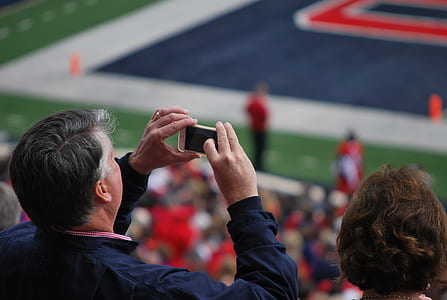 man wearing blue jacket holding up white Android smartphone in front of face thumbnail