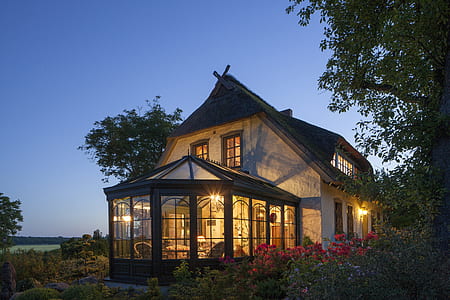 white and brown wooden house with lights turned on near plants during golden hour thumbnail