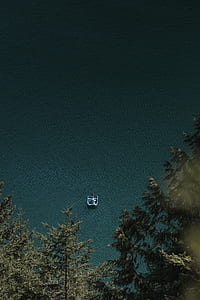 person riding boat on body of water near trees thumbnail