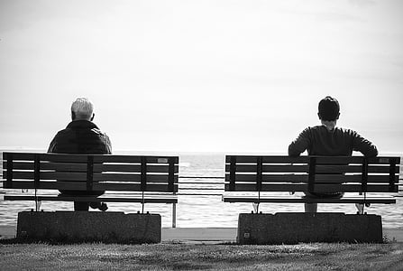 grayscale photography of men sitting on bench thumbnail
