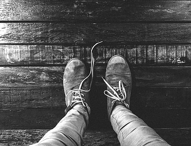 person wearing pair of sneakers in greyscale photography thumbnail