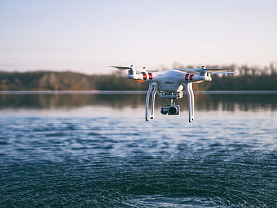 red and white DJI Phantom 3 flying over body of water during daytime thumbnail