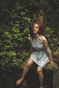 woman in dress sitting on rock near plants thumbnail