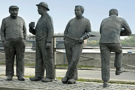 four men statue near fence and road thumbnail