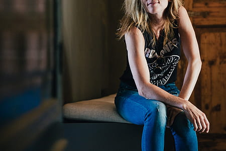 A young blonde woman in punk wear sitting with her hands on knees thumbnail