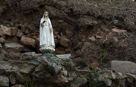 white ceramic figurine on rock formation thumbnail