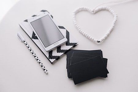 Black-and-white notebook and a white smartphone with various items thumbnail