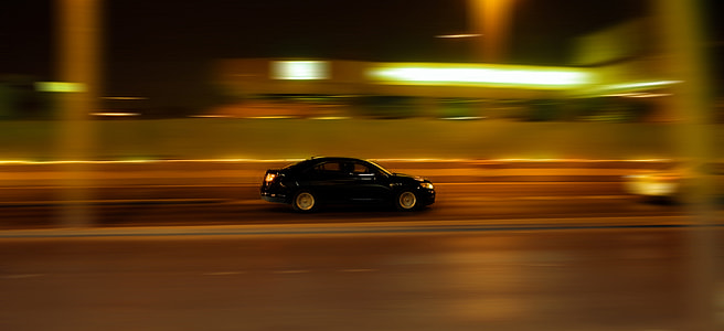 panning photography of black sedan on road near other vehicle thumbnail