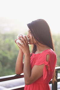 woman sipping beverage on white mug at balcony thumbnail