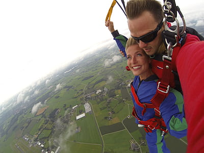 Couple Wears Red and Blue Long-sleeved Overalls and Body Harness With Parachute on Mid-air thumbnail