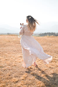 women's standing on grass field with hugging a dog thumbnail