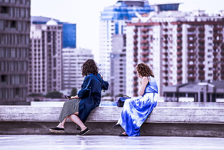 two women sitting on edge of rooftop thumbnail