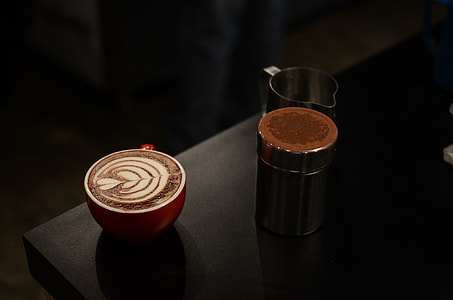 red and white ceramic cup on black wooden surface thumbnail