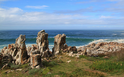 rock formation near body of water under blue skies thumbnail