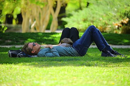 woman lying on man's stomach on green grass during daytime thumbnail