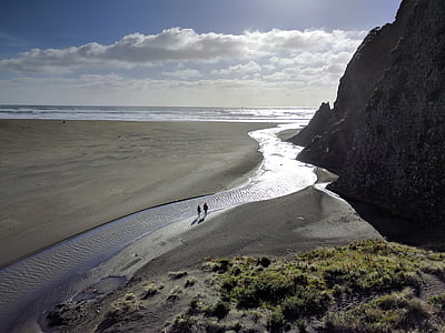 two person walking on shoreline near mountain thumbnail