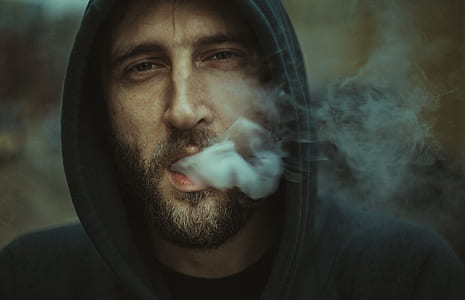 man in black hoodie releasing smoke through mouth thumbnail