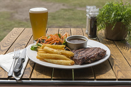 grilled meat beside fries and sauce on ceramic plate on brown wooden table thumbnail