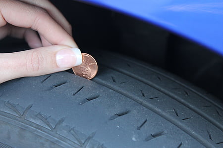 person holding coin near vehicle tire thumbnail
