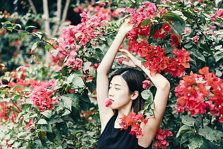 woman leaning on red petaled plants posing thumbnail