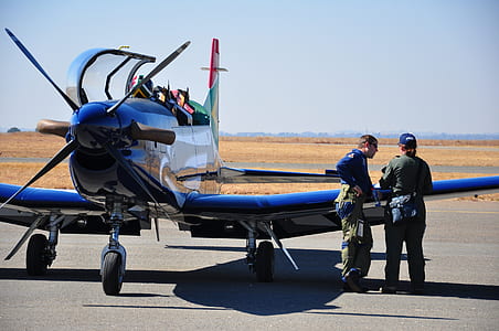 man beside woman behind blue monoplane thumbnail