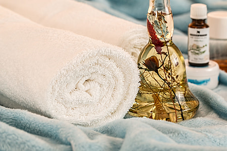 rolled bath towel beside brown liquid filled bottle thumbnail