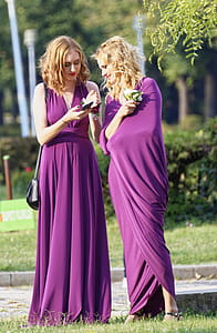 Two Women Wearing Purple Dresses on Grass Field thumbnail