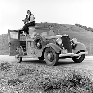 grayscale photography of woman sitting on roof of vintage vehicle thumbnail
