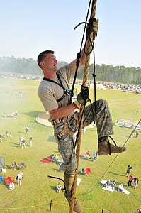 man in beige crew-neck T-shirt and green pants climbing in brown rope thumbnail